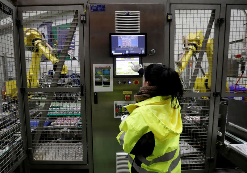 A worker operates robotic arms sorting yogurts at a distribution centre near Prague