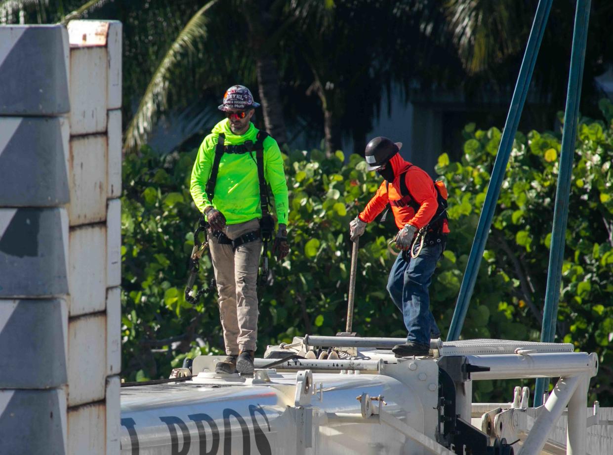 Workers make their way across a large crane at the Royal Poinciana Playhouse construction site April 5.