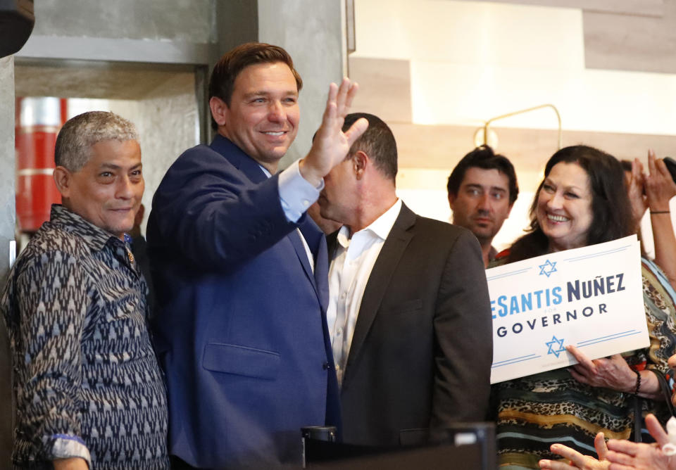 Florida Republican gubernatorial candidate Ron DeSantis, second from left, waves to supporters as he arrives at a campaign stop at Mo's Bagels & Deli Tuesday, Oct. 23, 2018, in Aventura, Fla. The candidates for Florida governor are scheduled to debate for the second and final time, three days after their first testy encounter. DeSantis and Democrat Andrew Gillum will meet Wednesday night, Oct. 24, 2018, at a community college near Fort Lauderdale. (AP Photo/Wilfredo Lee)