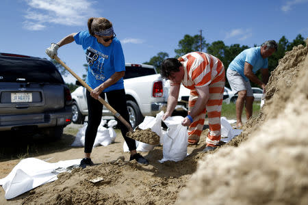 An inmate with the Hancock County Department of Corrections helps Janice Labat fill a bag with sand as Tropical Storm Gordon approaches Bay St. Louis, Mississippi, U.S., September 4, 2018. REUTERS/Jonathan Bachman