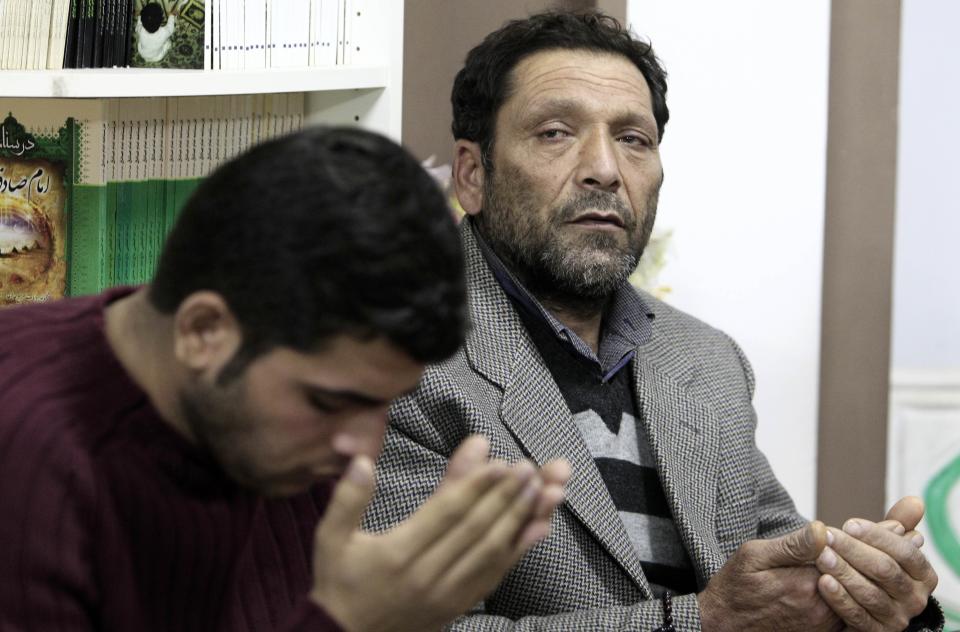 Afghan Fadi Mohamed, a survivor after a boat capsized, right, who lost his wife and three of his four children, pray with his son at a makeshift basement mosque in western Athens on Friday, Jan. 24, 2014. Twelve people, mostly children, are believed to have perished in Monday's sinking. Only two bodies have been found. Greece's merchant marine minister said Friday the survivors of a fatal migrant boat sinking changed their accounts of the incident, initially saying the Greek Coast Guard saved them but later accusing it of badly mishandling the rescue operation. (AP Photo/Thanassis Stavrakis)