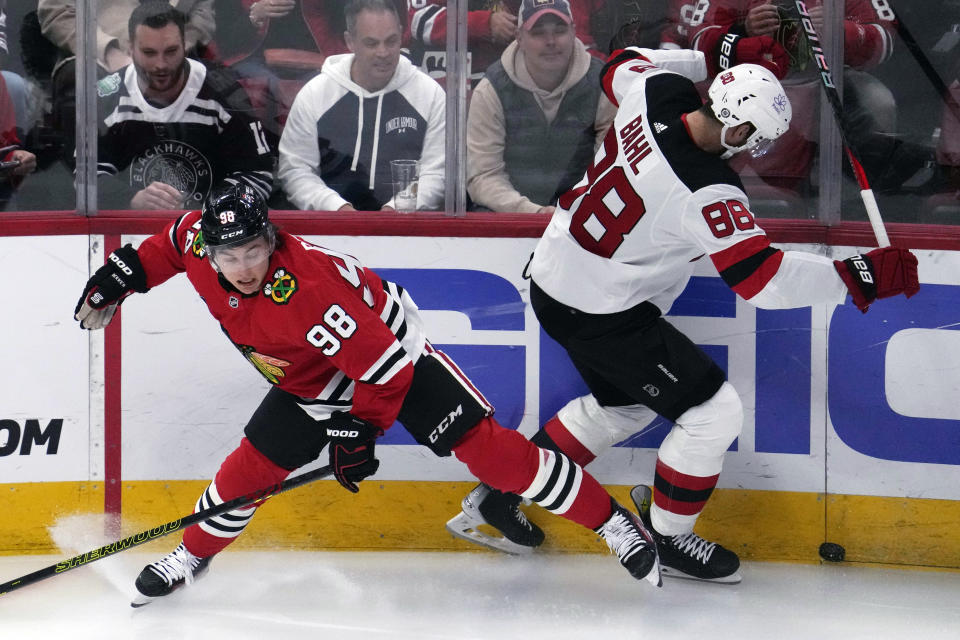 Chicago Blackhawks center Connor Bedard, left, and New Jersey Devils defenseman Kevin Bahl, right, battle for the puck during the first period of an NHL hockey game in Chicago, Sunday, Nov. 5, 2023. (AP Photo/Nam Y. Huh)