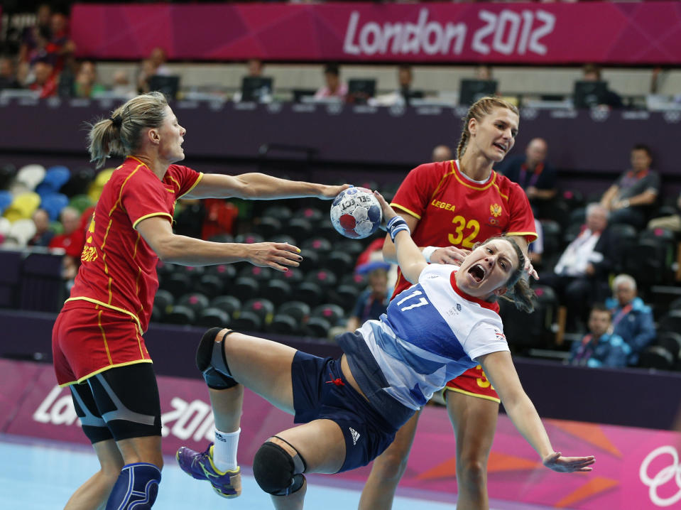 Ewa Palies of Great Britain, center, falls after being tackled by Maja Savic, left, and Katarina Bulatovic, right, of Montenegro during their women's handball preliminary match at the 2012 Summer Olympics, Saturday, July 28, 2012, in London. (AP Photo/Vadim Ghirda)