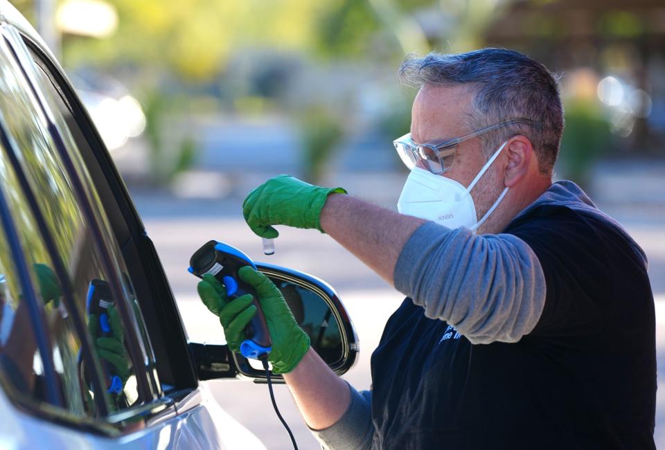 Eddie Irizarry, a test administrator, collects a vial at a saliva COVID-19 testing site, operated by Arizona State University and the Arizona Department of Health Services, on Jan. 26, 2022, in Scottsdale, Arizona.