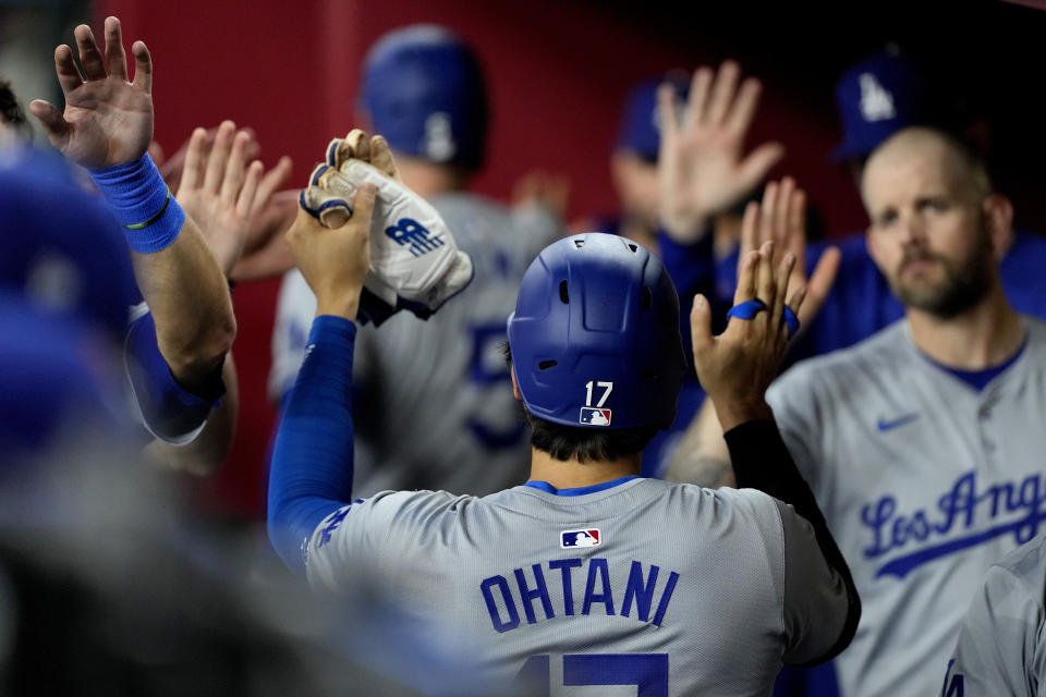 Los Angeles Dodgers' Shohei Ohtani (17) high fives teammates after scoring on a ground rule double hit by Teoscar Hernández during the fifth inning of a baseball game against the Arizona Diamondbacks, Monday, April 29, 2024, in Phoenix. (AP Photo/Matt York)