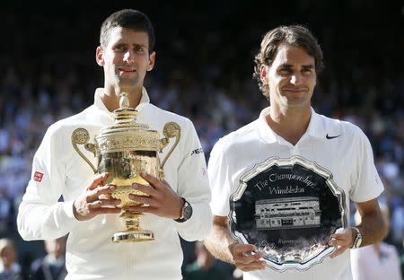 Novak Djokovic of Serbia holds the winner's trophy after defeating Roger Federer (R) of Switzerland, holding the runner-up's trophy, in their men's singles finals tennis match on Centre Court at the Wimbledon Tennis Championships in London July 6, 2014. REUTERS/Stefan Wermuth