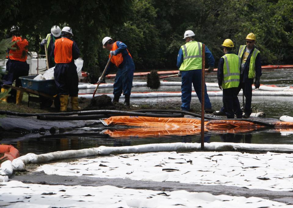 FILE - In this July 30, 2010 file photo, crews clean up oil, from a ruptured pipeline, owned by Enbridge Inc, near booms and absorbent materials where Talmadge Creek meets the Kalamazoo River as in Marshall Township, Mich. Federal investigators are expected to present their findings Tuesday, July 10, 2012 on the likely cause of a pipeline rupture that spilled more than 800,000 gallons of crude oil into the river nearly two years ago. (AP Photo/Paul Sancya, File)