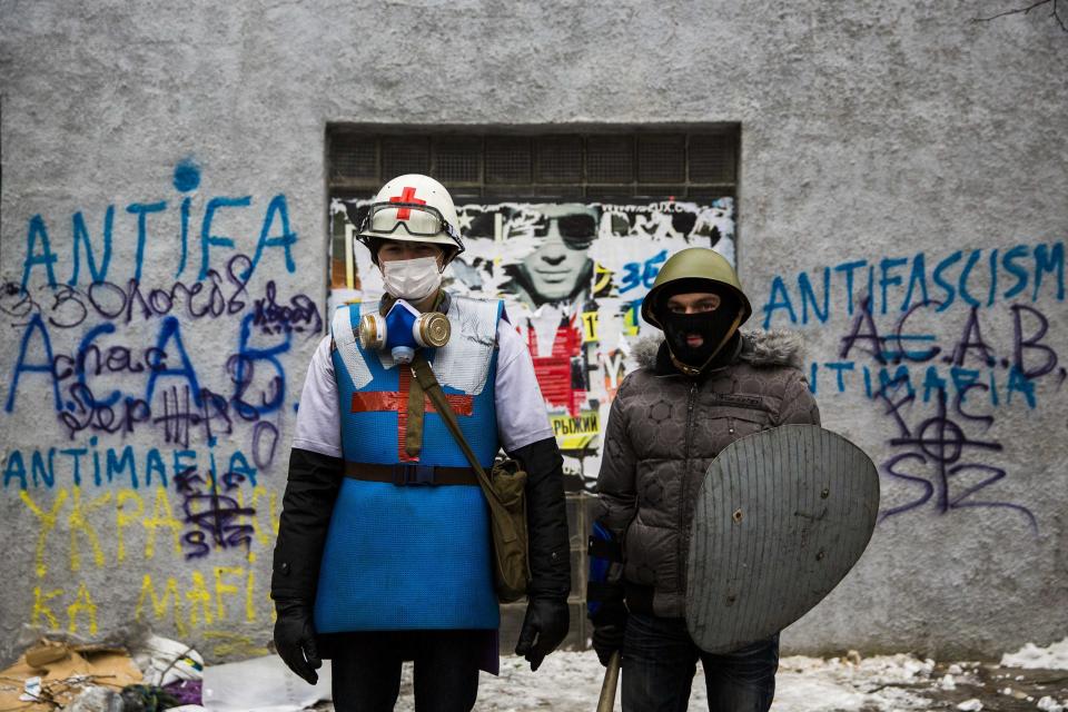 A medic of the anti-government protest camp poses for a portrait with his security guard at the barricades near the site of clashes with riot police in Kiev