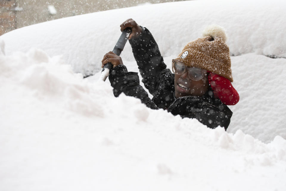 Zaria Black, 24, from Buffalo, clears off her car as snow falls Friday, Nov. 18, 2022, in Buffalo, N.Y. A dangerous lake-effect snowstorm paralyzed parts of western and northern New York, with nearly 2 feet of snow already on the ground in some places and possibly much more on the way. (AP Photo/Joshua Bessex)