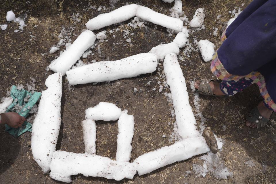 Girls play with ice pieced together from sleet that fell the previous day on the Cconchaccota community, in the Apurimac region of Peru, Saturday, Nov. 26, 2022. The rainy season in this part of South America should have started in September, but the area is experiencing its driest period in almost half a century, affecting more than 3,000 communities in the central and southern Andes of Peru. (AP Photo/Guadalupe Pardo)