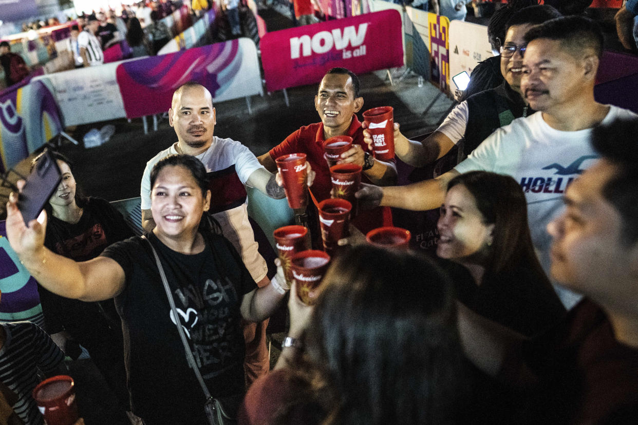 Hinchas de Filipinas se toman una selfi después de comprar cerveza Budweiser en una zona para aficionados durante el Mundial en Doha, Catar, el 1.° de diciembre de 2022. (Erin Schaff/The New York Times).