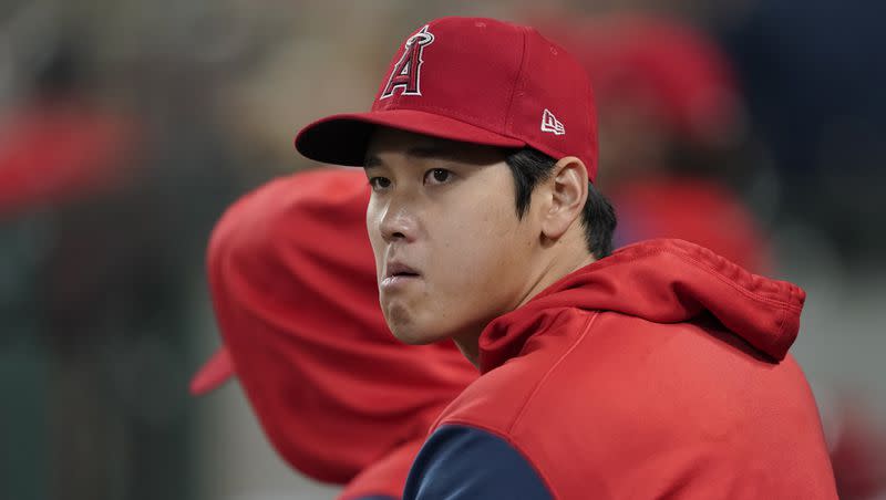 Los Angeles Angels’ Shohei Ohtani looks out from the dugout during the sixth inning of a baseball game against the Seattle Mariners, Friday, June 17, 2022, in Seattle.