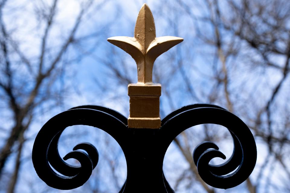 A golden finial sits atop the restored 100-year-old metal arch marking the entrance to Clifton's Rawson Woods Bird Preserve.