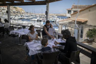 FILE- In this Tuesday, June 2, 2020 file photo, diners apply hand sanitizer provided by staff at a seafood restaurant in Marseille, southern France. The coronavirus pandemic is gathering strength again in Europe and, with winter coming, its restaurant industry is struggling. The spring lockdowns were already devastating for many, and now a new set restrictions is dealing a second blow. Some governments have ordered restaurants closed; others have imposed restrictions curtailing how they operate. (AP Photo/Daniel Cole, File)