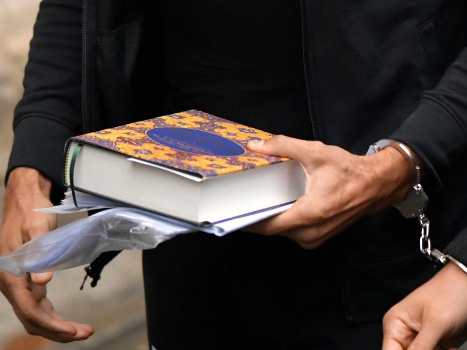 Tate holding the Quran as he went into court on Tuesday (AP)