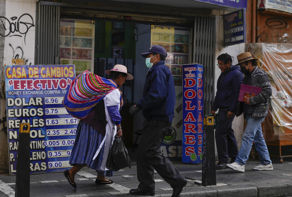 FILE - Pedestrians walk by a currency exchange shop in La Paz, Bolivia, June 12, 2024. With prices surging, dollars scarce and lines snaking away from fuel-strapped gas stations, protests in Bolivia have intensified over the economy's precipitous decline. (AP Photo/Juan Karita, File)