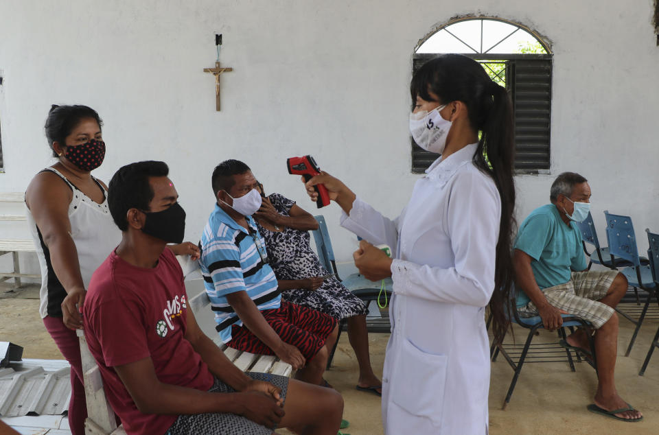 A health worker checks the temperature of the locals as she tests for COVID-19 at the Indigenous Park, a tribal community in the outskirts of Manaus, Amazonas state, Brazil, Thursday, Jan. 7, 2021. Medical teams are scrambling to assist indigenous people living in outlying areas of Manaus, where medical care is scarce after authorities issued a "State of Emergency" due to rising numbers of infection numbers in Amazonas State. (AP Photo/Edmar Barros)