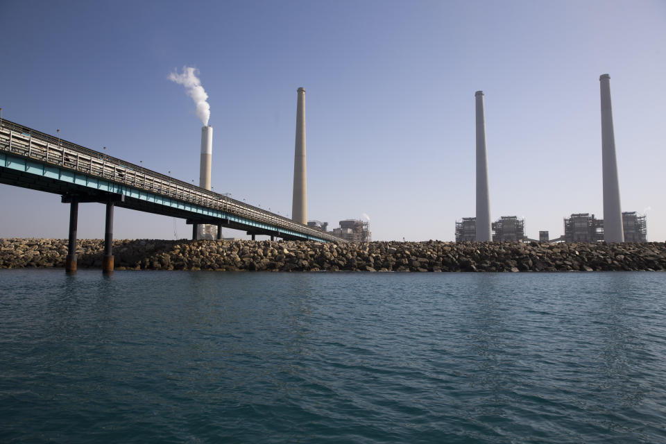 This Monday, Jan. 21, 2019 photo, shows a power plant on the Mediterranean Sea, in the northern Israeli city of Hadera. The giant power plant with billowing smoke may not look like the most natural habitat for sea life. But the hot water gushing from the plant is drawing schools of sharks that are increasingly endangered by overfishing in the Mediterranean Sea. Now the hotspot is also drawing tourists. (AP Photo/Ariel Schalit)