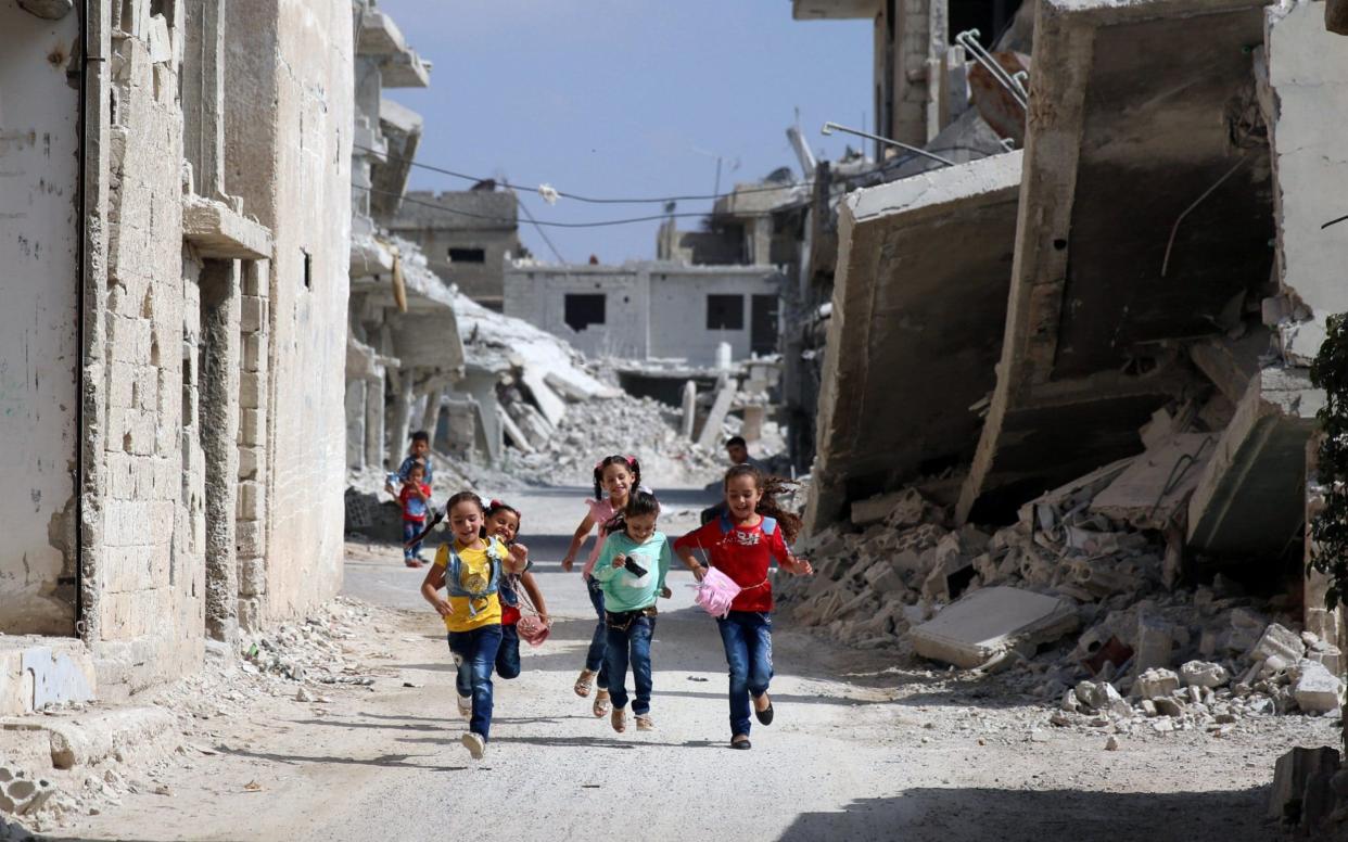 Children run along a damaged street as they celebrate the first day of the Muslim holiday of Eid al-Adha in Deraa when it was under the control of rebels - REUTERS