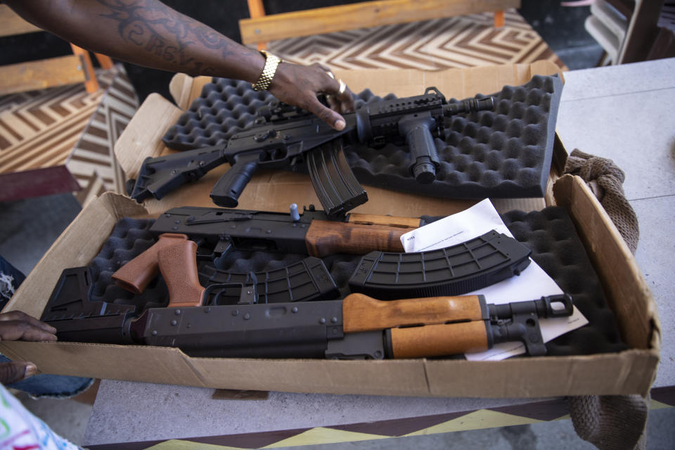 A G9 gang coalition member unpacks weapons that include American-made AK rifles with ammunition, in Port-au-Prince, Haiti, Wednesday, Oct. 6, 2021. While some gangs have turned to kidnapping, like those who captured 17 missionaries and their relatives, the G9 coalition has taken control of the port district, gaining a stranglehold on the country’s economy. (AP Photo/Rodrigo Abd)