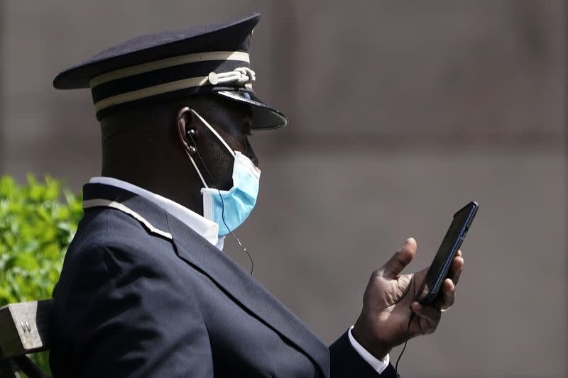 A doorman looks at his phone during the outbreak of Coronavirus disease (COVID-19), in the Manhattan borough of New York City