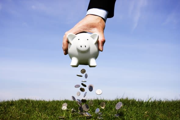 Businessman shaking money out of a piggy bank