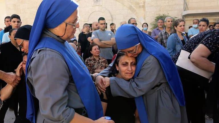 Las mellizas María del Perpetuo Socorro (izq) y María del Pilar Llerena Vargas consuelan familiares de víctimas del bombardeo israelí que impactó en la estructura de la iglesia ortodoxa San Porfirio el 19 de octubre