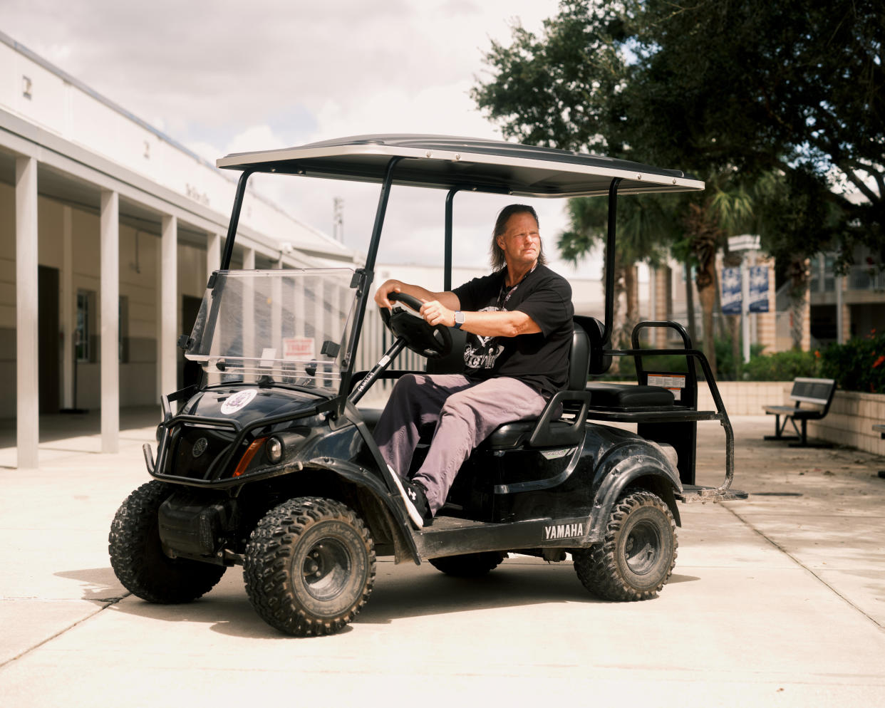 Lyle Lake, agente de seguridad de la escuela secundaria Timber Creek en Orlando, Florida, patrulla en un carrito de golf durante la hora del almuerzo, en busca de alumnos que infrinjan la prohibición de utilizar celulares impuesta por el distrito escolar. (Zack Wittman/The New York Times)