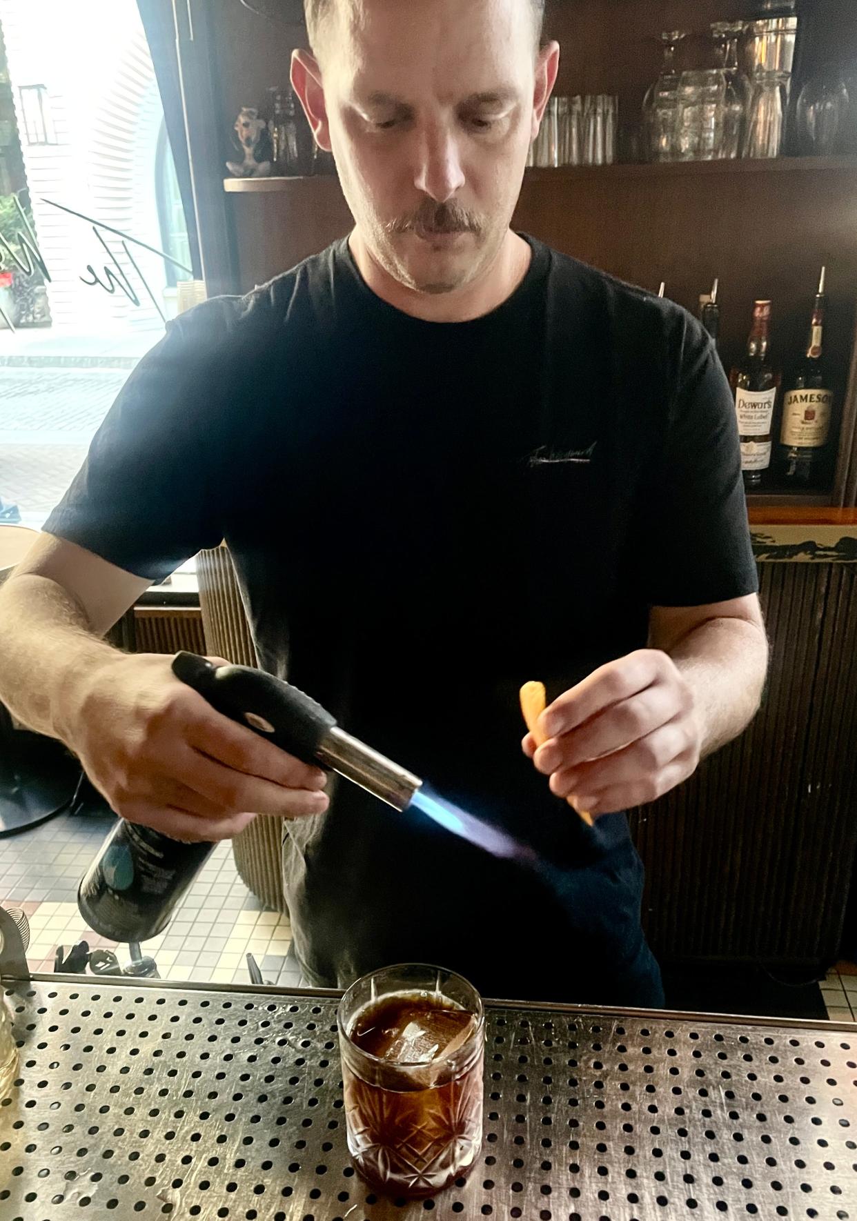 The Wayward's bartender David Hine torches orange peel to create the smoke for his "Revolver."