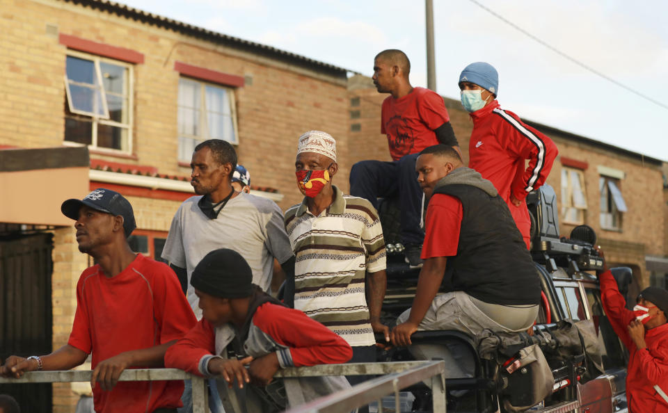 In this May 2, 2020, rival gang members on a delivery truck help distribute food in the Manenberg neighborhood of Cape Town, South Africa. A preacher recruited the street gangs for the deliveries on the violent streets during the coronavirus lockdown. The gang members deliver bread, flour and vegetables to homes and soup kitchens. (AP Photo/Nardus Engelbrecht)