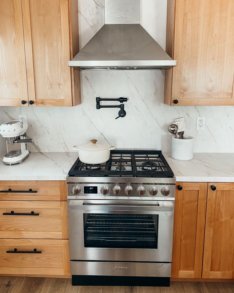 white kitchen with wood cabinets and marble counter and backsplash after makeover