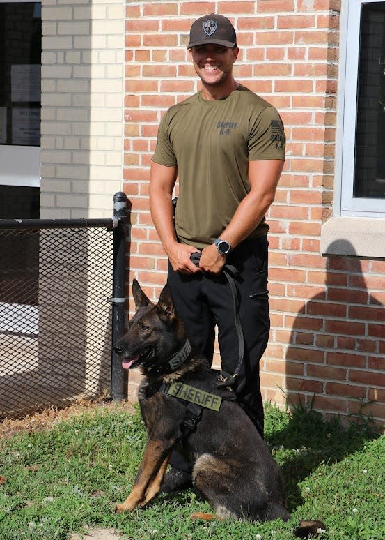 Donald Johnson poses for a photo with Kato, a drug detection dog who was recently reassigned to patrol work and may eventually either retire or be sold to a department in another state with stricter marijuana laws.