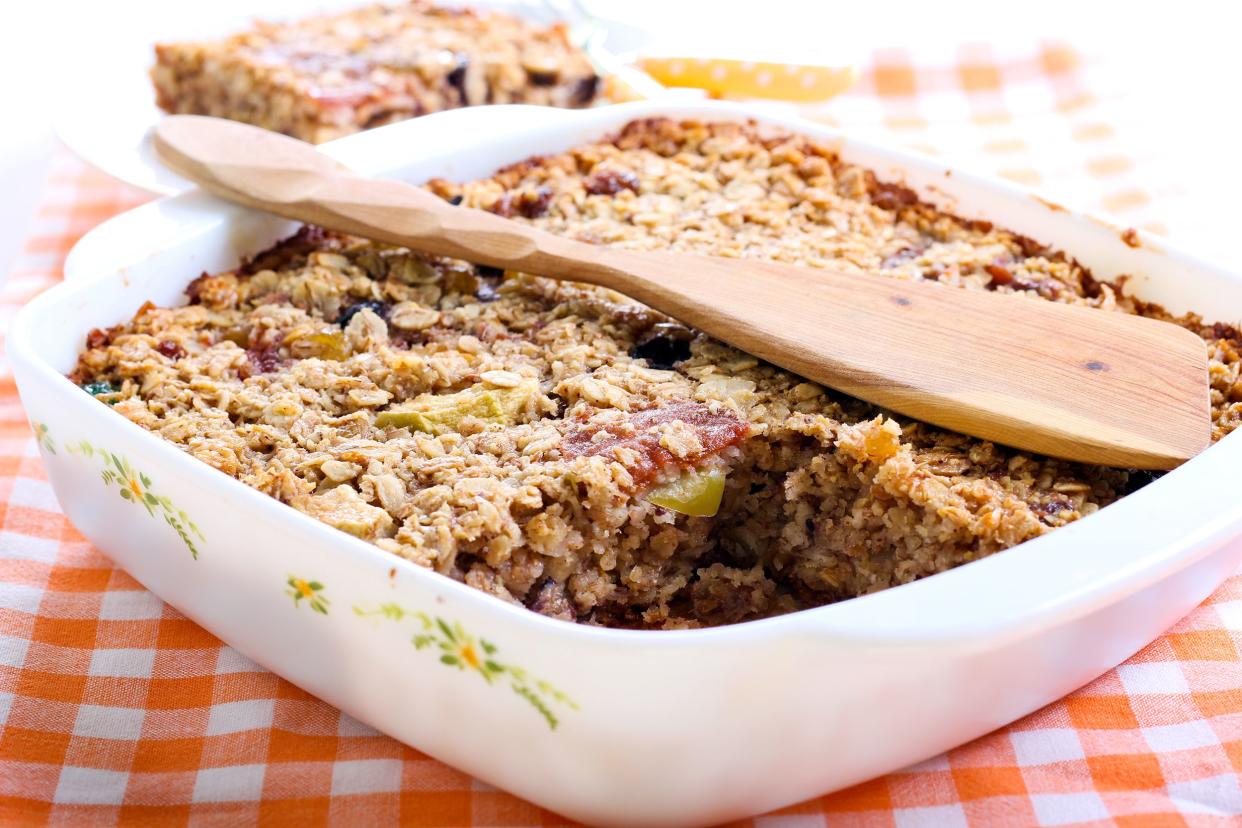 Baked Oatmeal with Applesauce in white rectangular baking dish with wood spatula on an orange checkered tablecloth