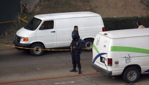 Police stand guard next to one of three trucks (back) in which several bodies were found in Guadalajara, Mexico, November 24. Fifty dead bodies have been discovered over the past two days in western Mexico, victims of a fierce war waged between the government and the nation's powerful drug cartels