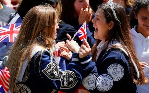 Students at Meghan's old school in Los Angeles wave flags at a pre-wedding celebration in the city - Credit: REUTERS/Mike Blake