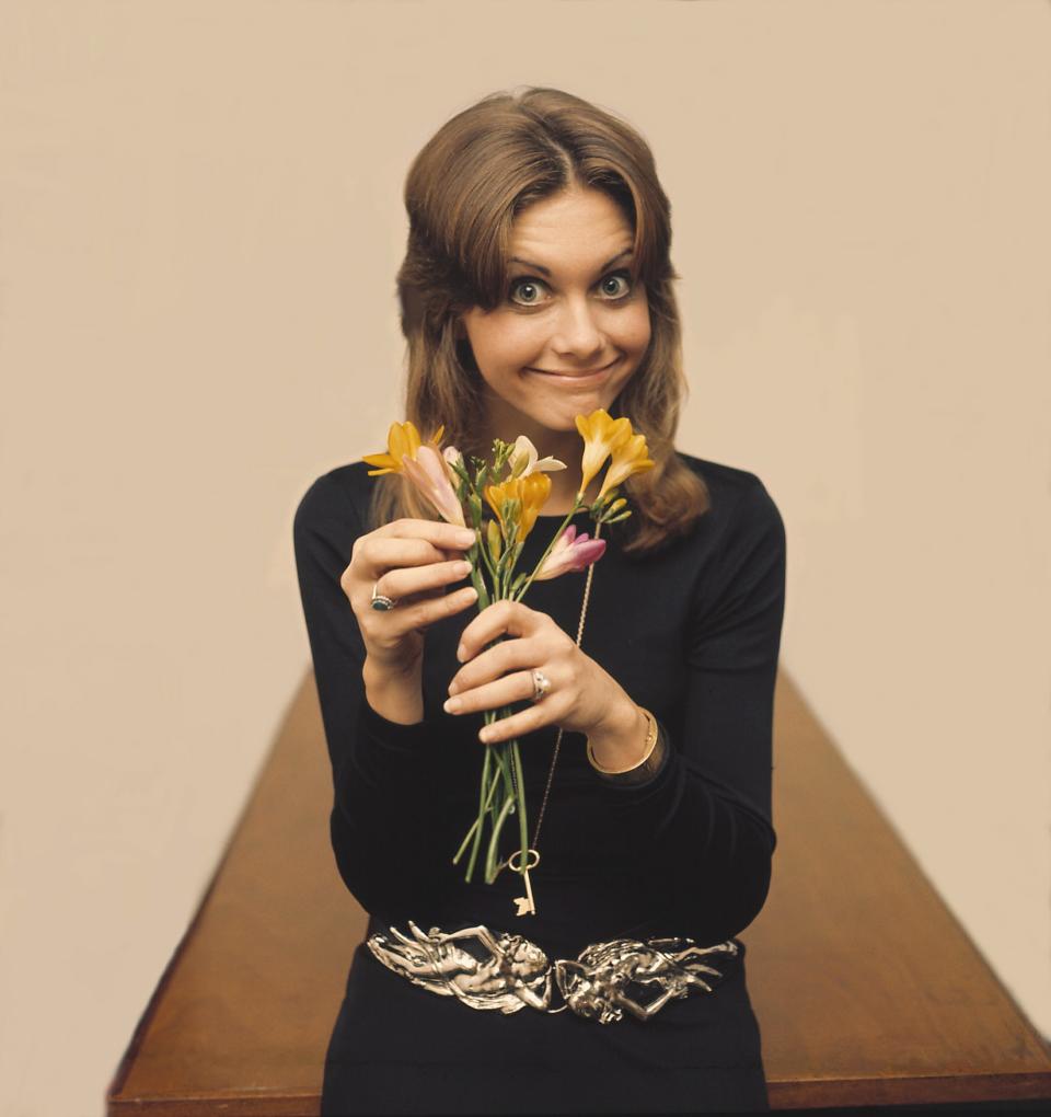 Olivia Newton-John smiling and holding flowers