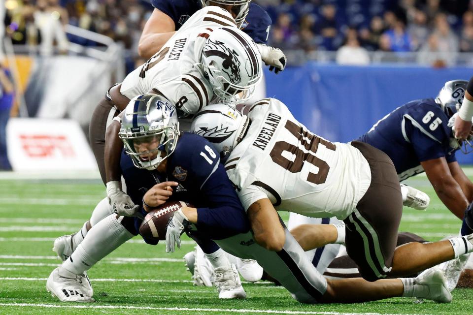 Nevada quarterback Nate Cox is sacked by Western Michigan's Marshawn Kneeland (94) and Ralph Holley (8) during the Quick Lane Bowl.