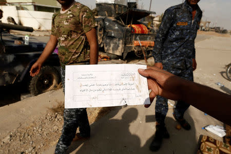 An Iraqi soldier shows an envelope which reads "Islamic State can be entrusted to deliver your God given right of charity from the rich", along a street of the town of al-Shura, which was recaptured from Islamic State (IS) on Saturday, south of Mosul, Iraq October 30, 2016. REUTERS/Zohra Bensemra