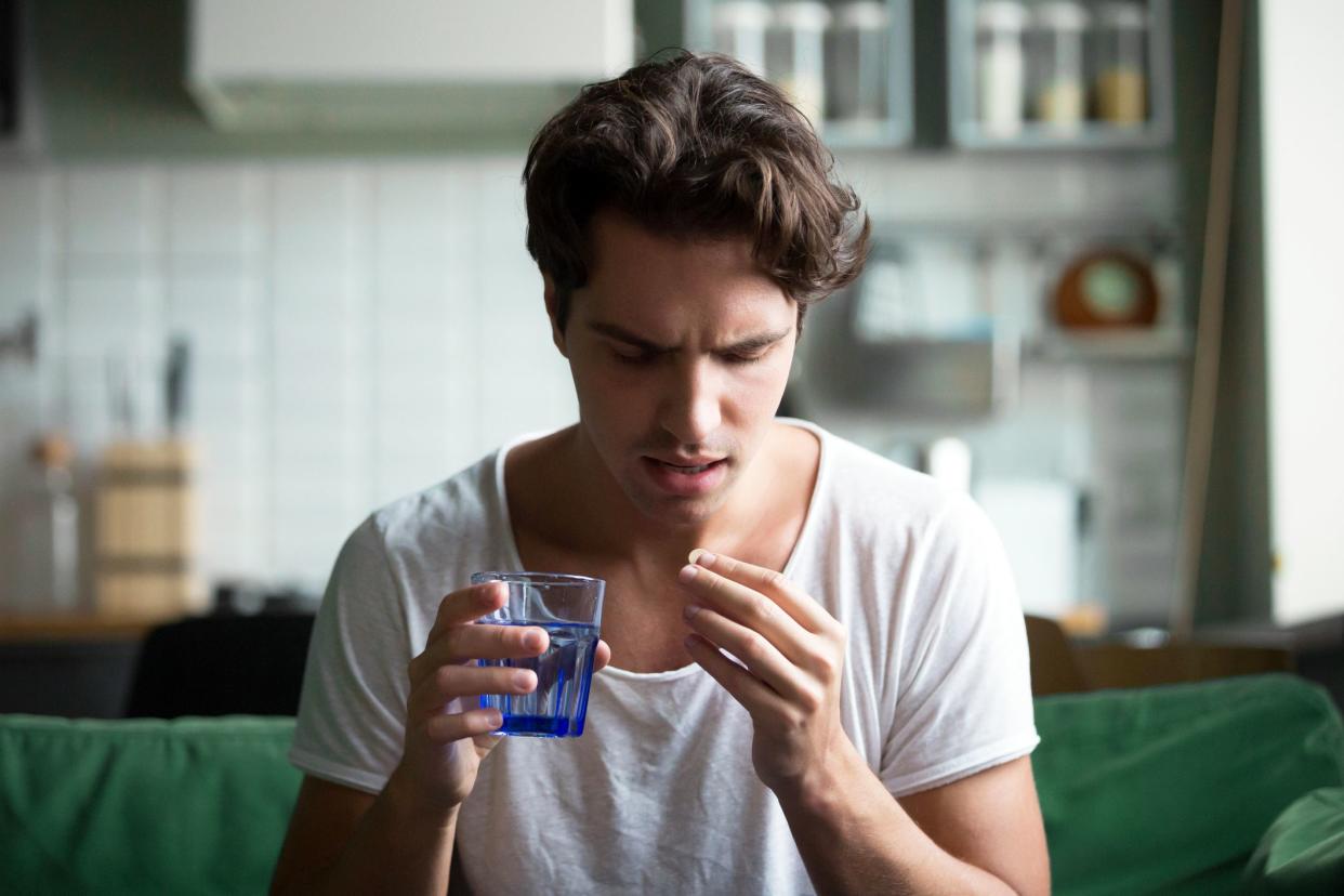 tense young man looking at pill he is about to take
