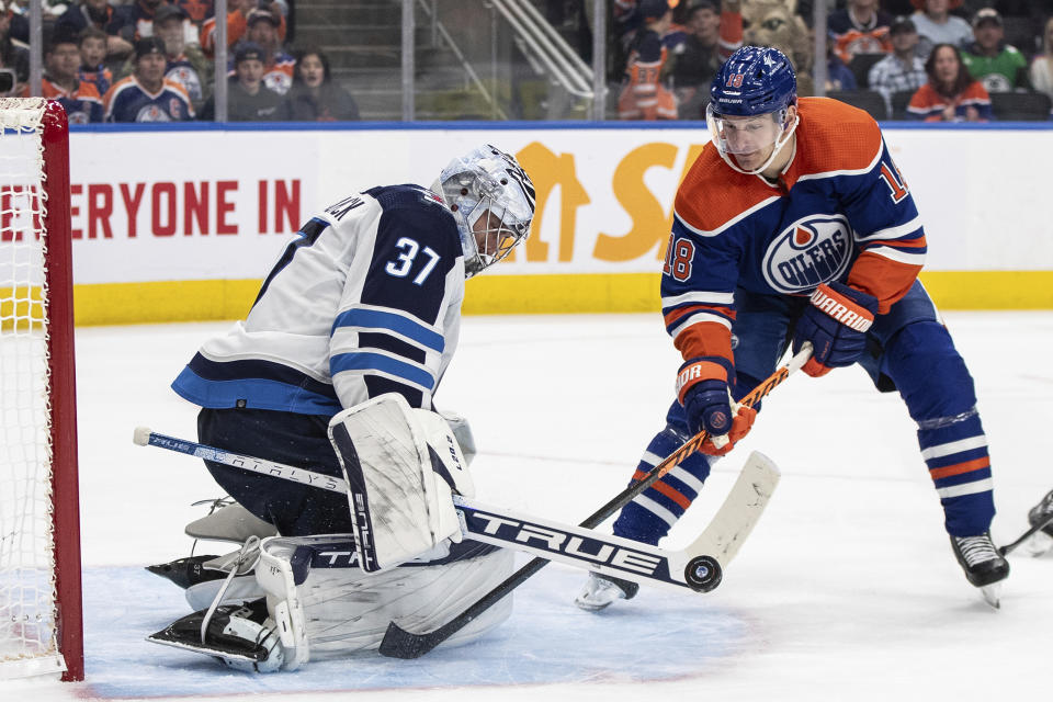 Winnipeg Jets goalie Connor Hellebuyck (37) makes the save on Edmonton Oilers' Zach Hyman (18) during the second period of an NHL hockey game in Edmonton, Alberta, Saturday, Oct. 21, 2023. (Jason Franson/The Canadian Press via AP)