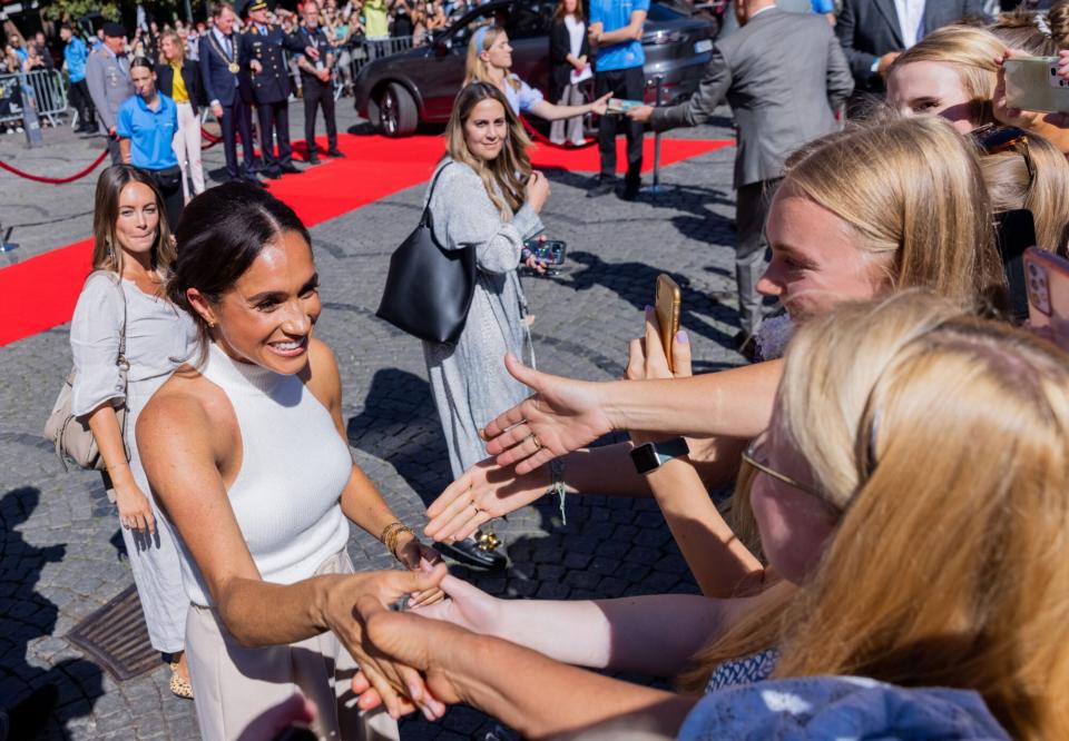 06 September 2022, North Rhine-Westphalia, Duesseldorf: Britain's Prince Harry (not pictured), Duke of Sussex, and his wife Meghan, Duchess of Sussex (l), come out of City Hall and talk to people who have been waiting outside. In the process, Meghan shakes hands with two young women. The prince and his wife are coming to Düsseldorf to promote the "Invictus Games" 2023, which Prince Harry helped launch. These are Paralympic competitions for soldiers who have been injured in war. Photo: Rolf Vennenbernd/dpa (Photo by Rolf Vennenbernd/picture alliance via Getty Images)