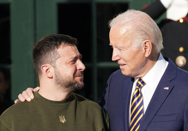 President Biden, in suit and tie, has his arm warmly around the shoulder of President Volodomyr Zelensky, in battle-green sweater, who expresses gratitude and emotion.
