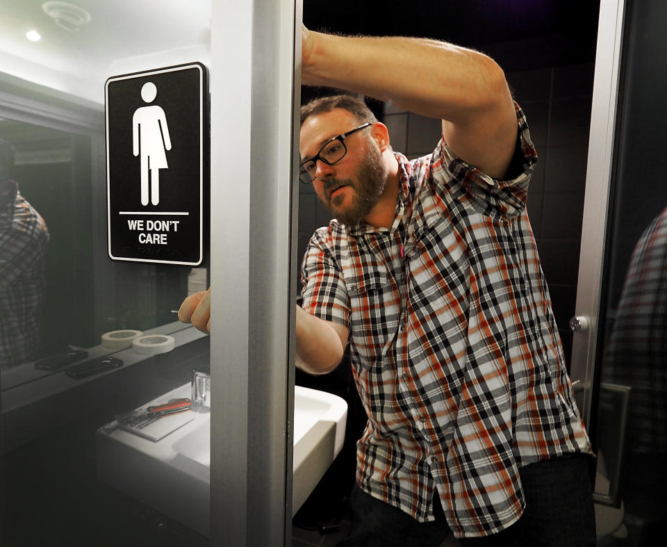 Museum Manager Jeff Bell puts up a gender neutral bathroom sign&nbsp;in the 21C Museum Hotel public restrooms on May 10, 2016, in Durham, North Carolina.