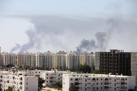 Smoke rises above buildings after heavy fighting between rival militias broke out near the airport in Tripoli July 23, 2014. REUTERS/Hani Amara