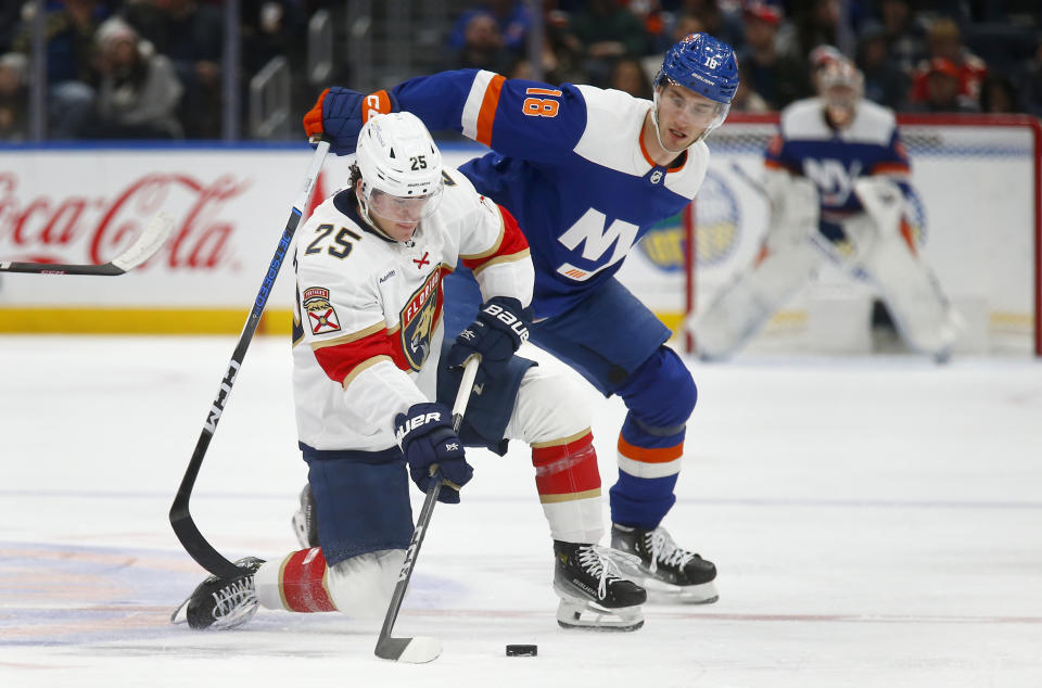 Florida Panthers forward Mackie Samoskevich (25) and New York Islanders forward Pierre Engvall (18) stay focused on the puck during the second period of an NHL hockey game, Saturday, Jan. 27, 2024, in Elmont, N.Y. (AP Photo/John Munson)