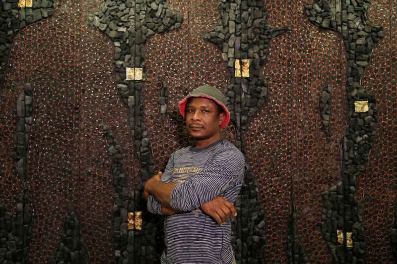 Uchay Chima, a Nigerian contemporary artist poses for a portrait in front of his artwork at the Museum of Contemporary Art in Lagos, Nigeria