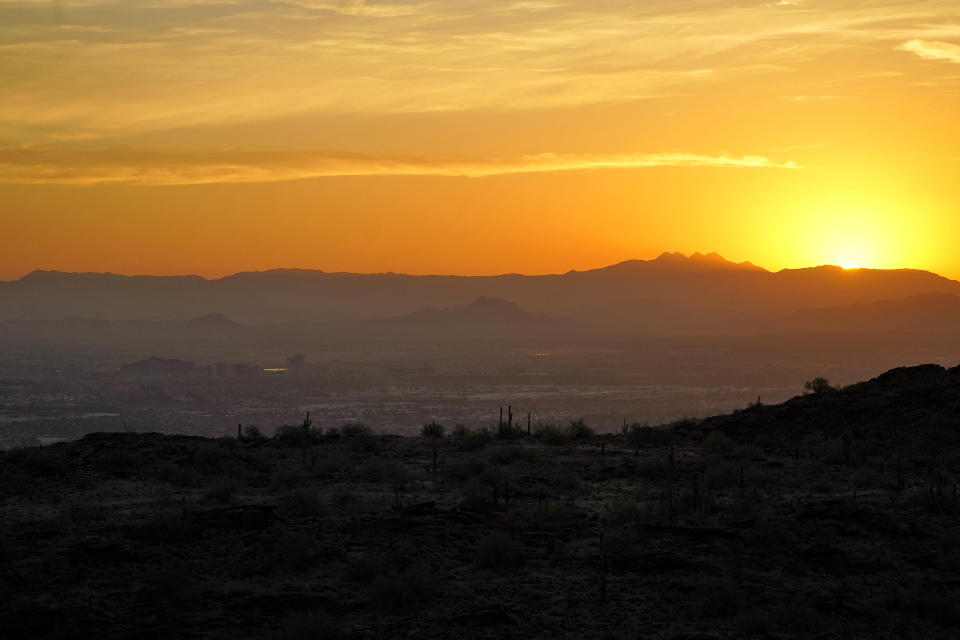 The sun rises over Tempe, Ariz., as seen from atop South Mountain, Monday, July 17, 2023 in Phoenix. Phoenix is set to break its own record for consecutive days of highs of at least 110 degrees. Around one-third of Americans are under some type of heat advisory, with the most blistering temperatures in the South and West, where even the regular simmer has turned up a notch. (AP Photo/Matt York)