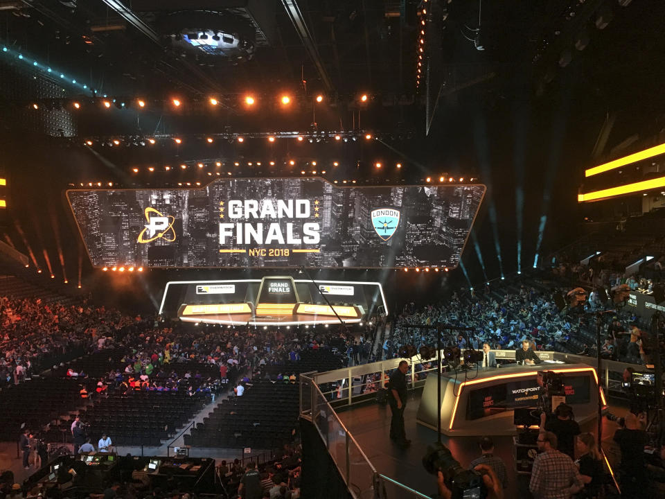 In this Friday, July 27, 2018, fans fill the arena as the stage is set for the Overwatch League Grand Finals' first night of competition, at the Barclays Center in the Brooklyn borough of New York. The Overwatch League is making a grand gamble: that its deep pockets and massive infrastructure can keep it atop the esports mountain even as Fortnite comes charging for the crown. (AP Photo/Terrin Waack)