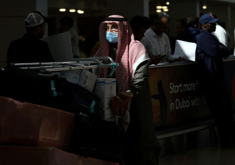 A traveller wears a mask as he pushes a cart with luggage at Dubai International Airport, after the UAE's Ministry of Health and Community Prevention confirmed the country's first case of coronavirus, in Dubai