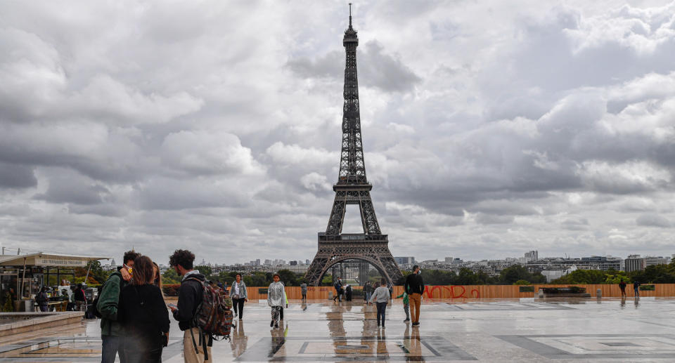 Photo shows people in the foreground of the Eiffel Tower in Paris, France.